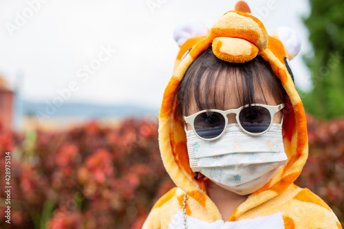 A cute Asian girl wearing a giraffe costume, Sunglasses travel in a new normal state with a face mask.