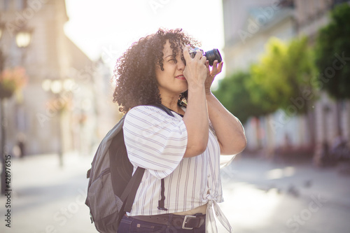 Woman taking photo on camera. Mixed race woman in the city. © liderina