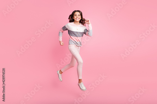 Full length photo of little beautiful young girl jump up run sale hurry isolated on pink color background