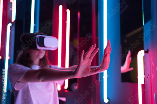 Slender woman in a white virtual reality helmet in cyberspace. Immersive entertainment of the future photo