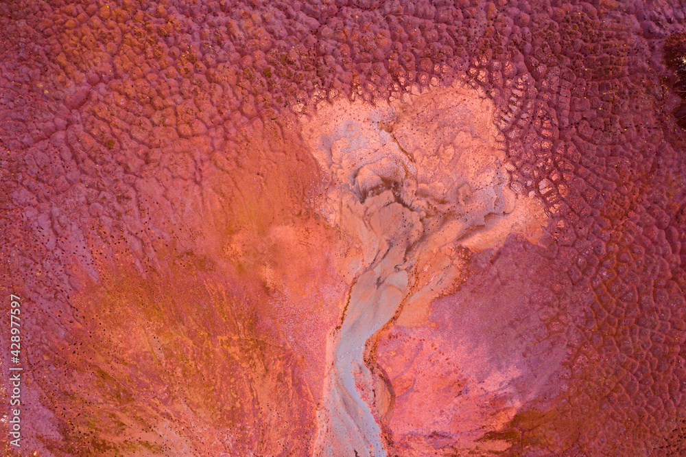 Aerial drone view of industrial chemicals dump site from ironlworks, dry red soil with animal paw prints, unique texture.
