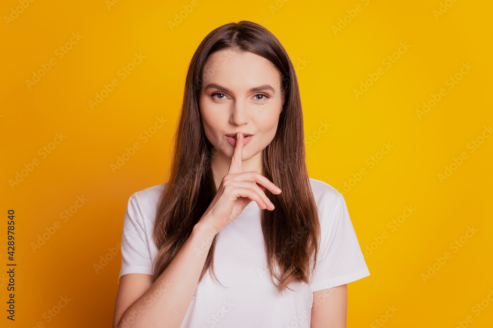 Photo of tender flirty lady finger close lips wear white t-shirt posing on yellow background Photo of tender flirty lady finger close lips wear white t-shirt posing on yellow background