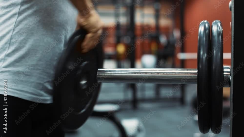 Male athlete taking weight off of a bar in a gym Male athlete taking weight off of a bar in a gym