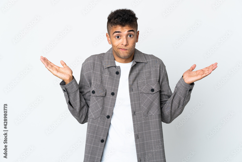 Young brazilian man isolated on white background having doubts while raising hands Young brazilian man isolated on white background having doubts while raising hands