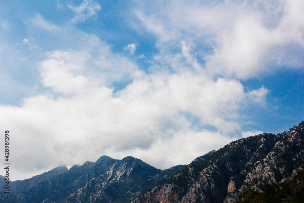 white clouds on a blue sky against the background of mountains white clouds on a blue sky against the background of mountains