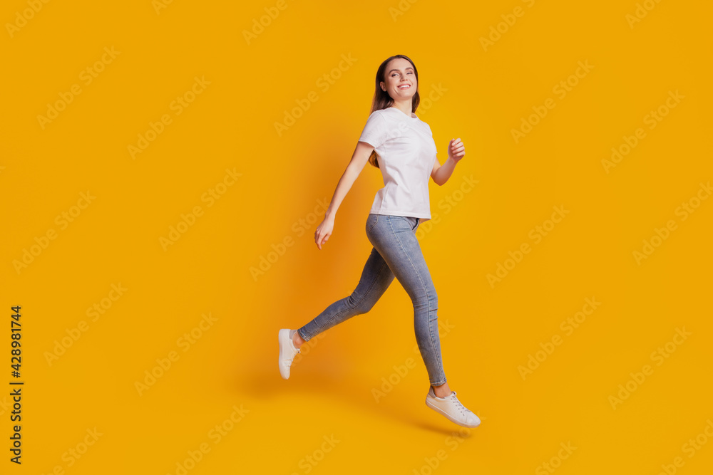 Photo of active sportive teen lady jump run wear white t-shirt posing on yellow background