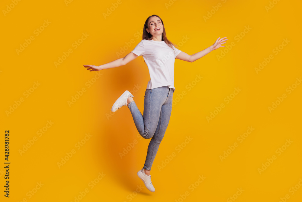 Photo of crazy energetic lady jump have fun wear white t-shirt posing on yellow background