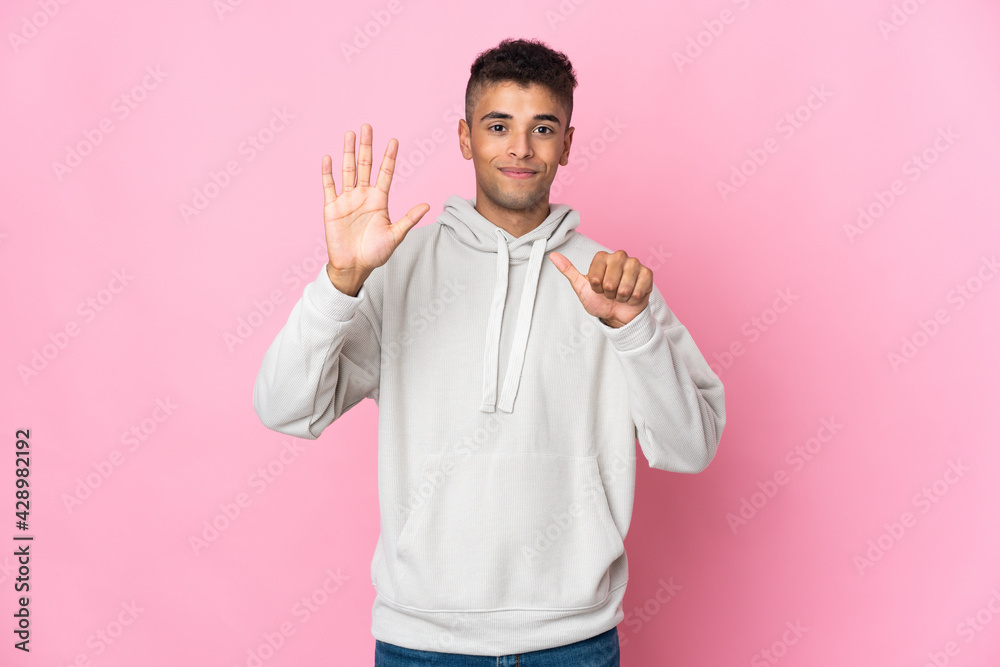 Young Brazilian man isolated on pink background counting six with fingers Young Brazilian man isolated on pink background counting six with fingers