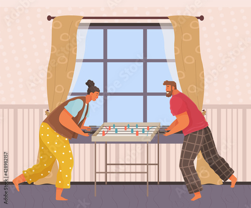 Cheerful couple with board game. Man and woman play table football together in room near stairs