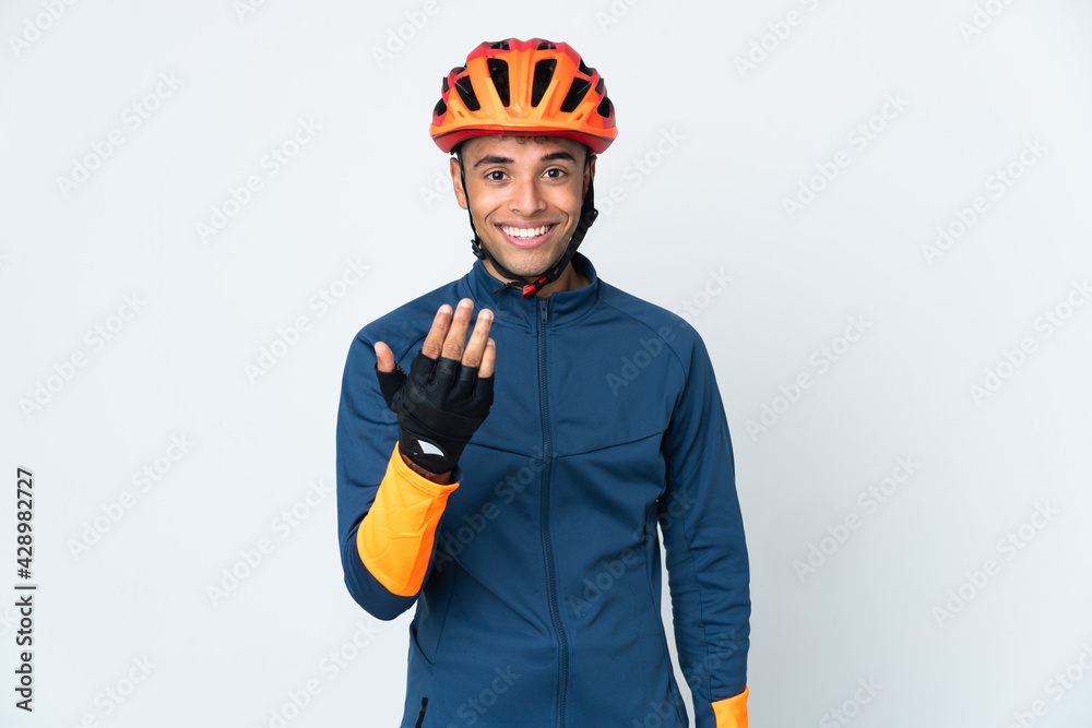 Young cyclist Brazilian man isolated on white background inviting to come with hand. Happy that you came - obrazy, fototapety, plakaty 