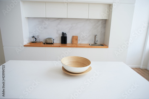 White countertop with a large light bowl for salad. Kitchen in the studio. Decor of a stylish room.