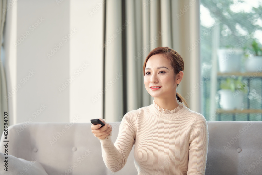 Happy young woman watching tv on sofa Happy young woman watching tv on sofa