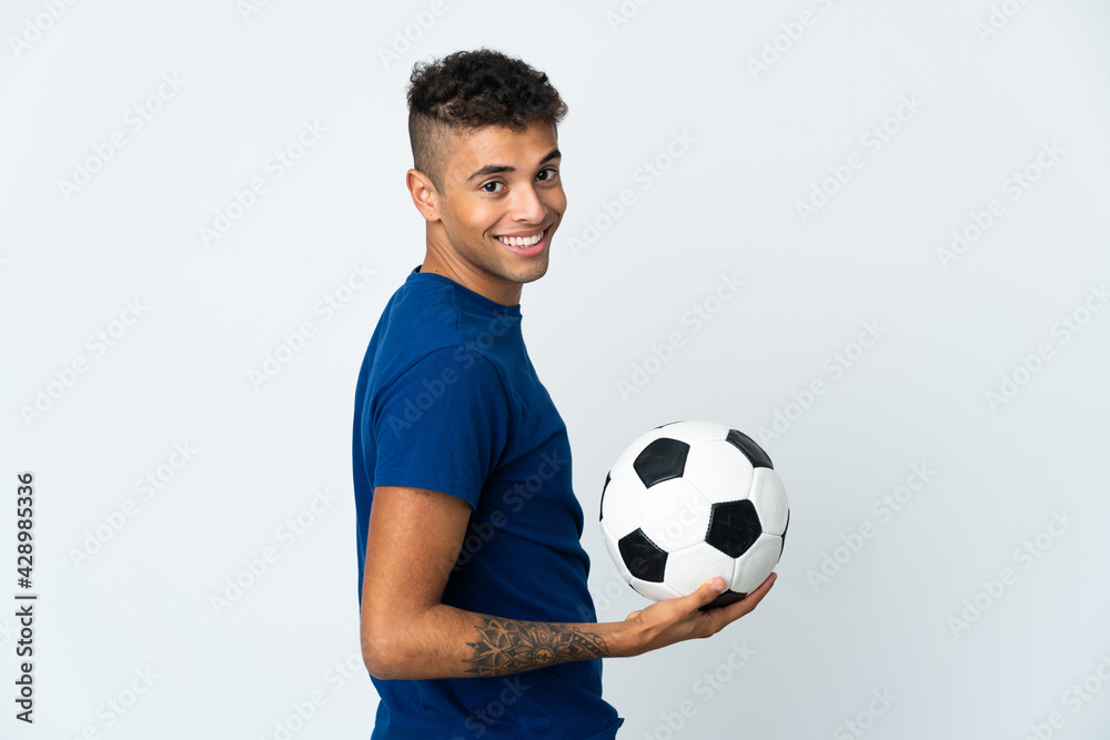 Young Brazilian man over isolated background with soccer ball