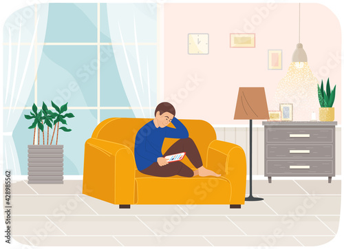Young man sitting on armchair with tablet, studying remotely, watches social media, serfing Internet