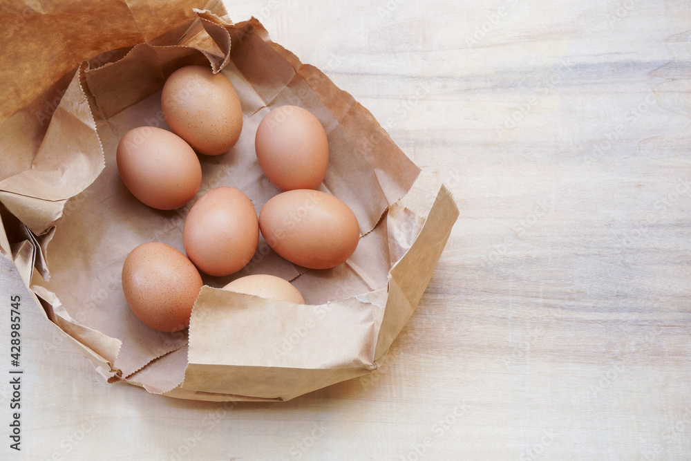 Brown egg in paper bag behind ,Fresh chicken eggs on wood table Brown egg in paper bag behind ,Fresh chicken eggs on wood table