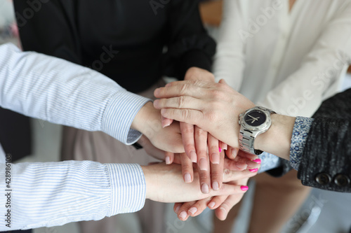 Closeup of many folded hands of businessmen in office