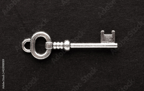 Decorative metal key on the empty black background © strannik_fox