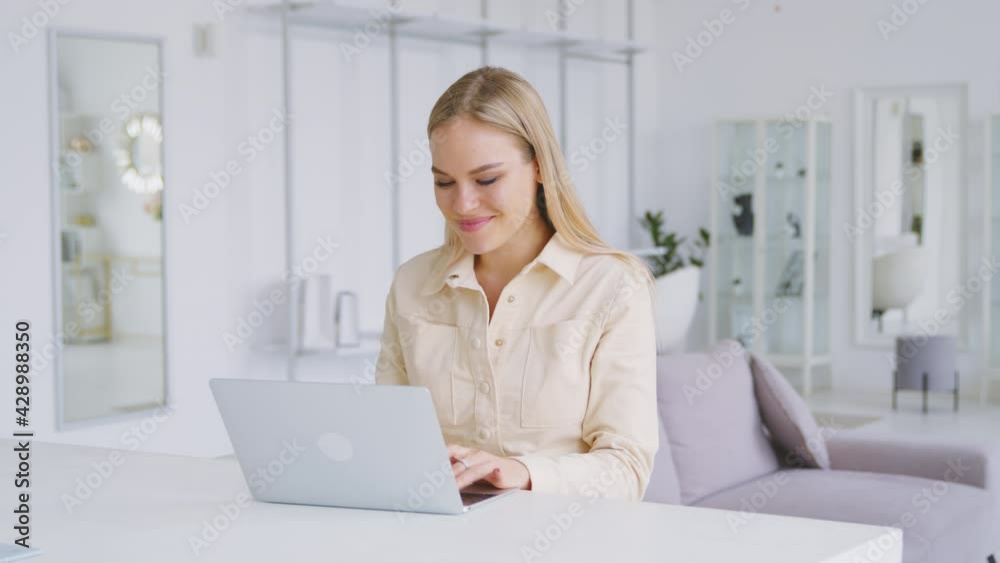 Attractive girl at the desk with a laptop in a white room. Portrait of young woman with laptop Attractive girl at the desk with a laptop in a white room. Portrait of young woman with laptop