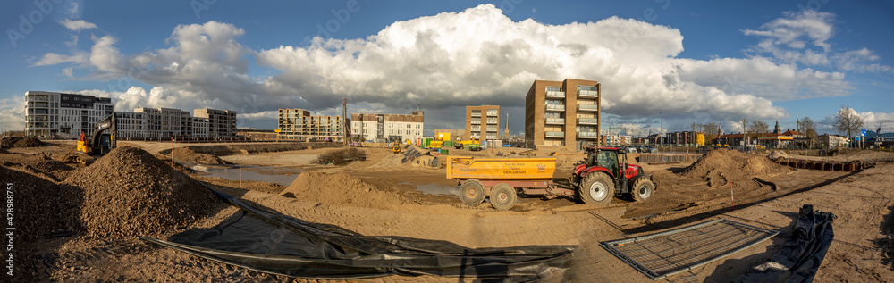 Panoramic view on Kade Zuid construction site of the new Noorderhaven neighbourhood in Dutch city of Zutphen,  The Netherlands, against a vibrant blue sky with bright clouds