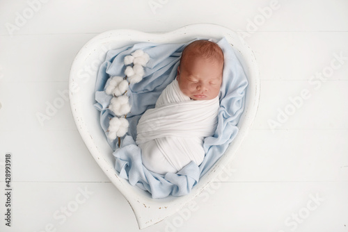 Cute sleeping newborn near flowers. Portrait of a newborn baby