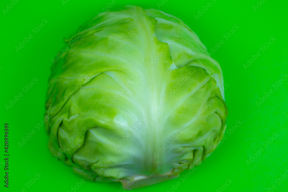 Fototapeta premium Green cabbage on the green background. Close up. Macro photo. Minimalism, original beautiful food photo.