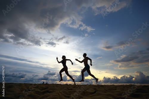 silhouettes of athletes running along the beach   sports summer in the warm sea  healthy rest  sports activity  summer vacation