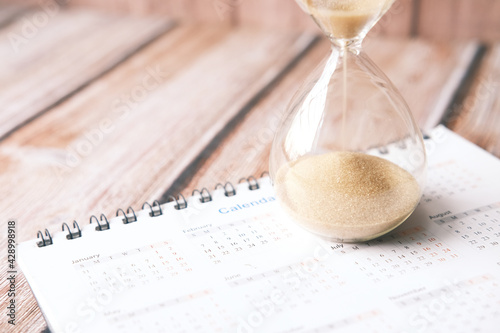 Принти на полотні hourglass on calendar on table, sand flowing through the bulb of sandglass