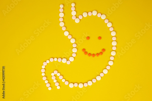 Fotografia A cheerful face in a stomach of pills on a yellow background