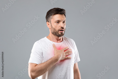 Картината върху платно Man with chest pain touching inflammated zone, grey background