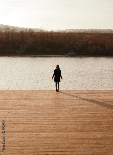 Woman in black coat enjoying sunset near river