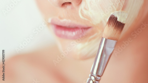 A picture of a young woman applying face powder in the bathroom