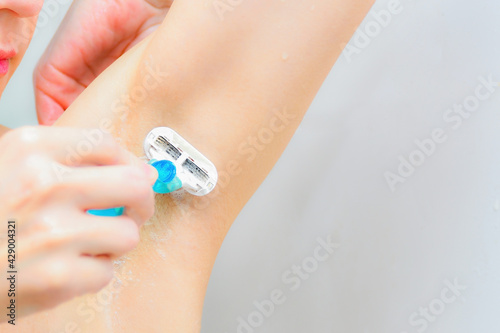 The girl in the shower shaves her armpits with a shaving machine © andov