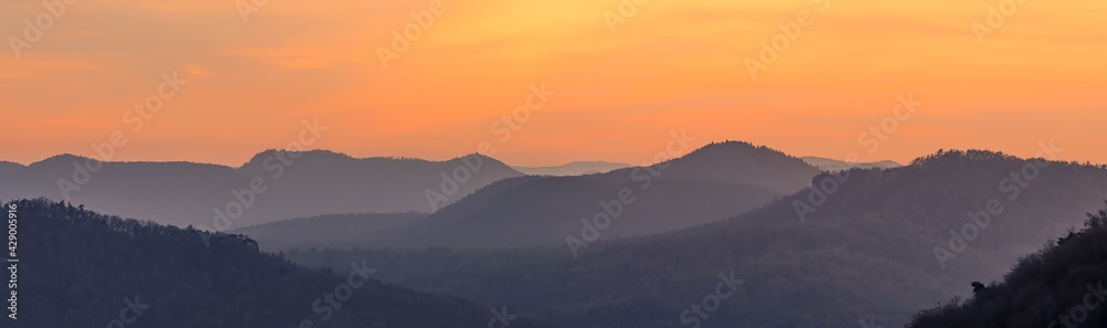 mountain layers after sunset during golden hour, orange sky, distant fog