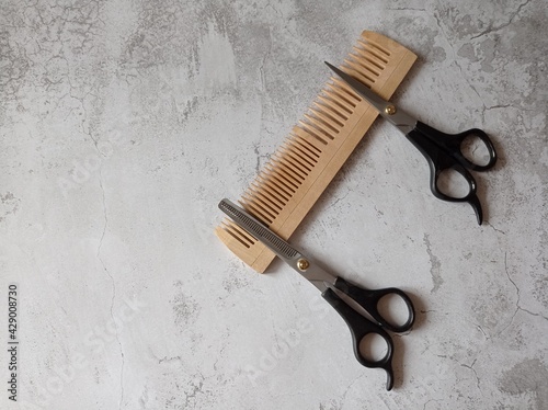 Two hair clippers are placed on a wooden comb on a light background. Copispace photo