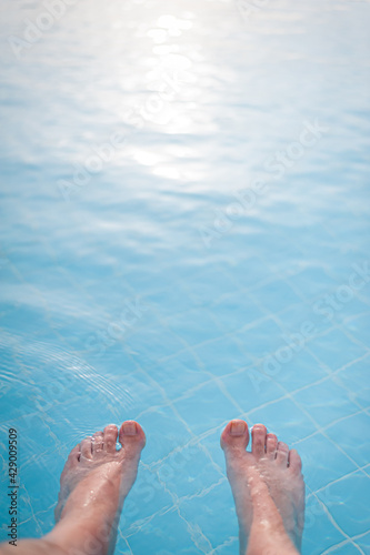 Overhead photo of feet on a background of water in swimming pool. Swimming pool, relax, health. © Jakub Rutkiewicz