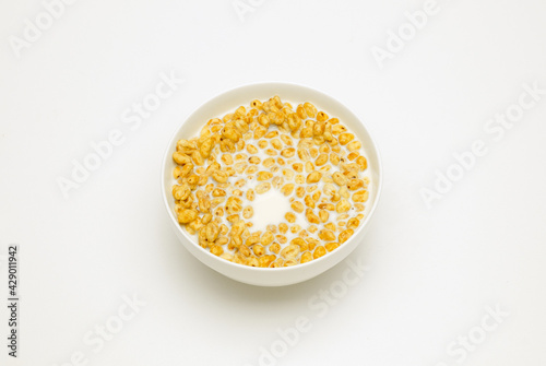 wheat flakes with milk in a white cup on a white background