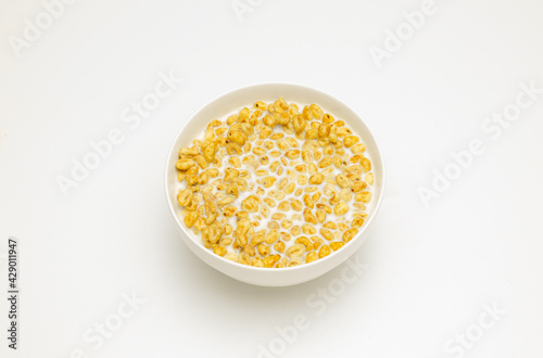wheat flakes with milk in a white cup on a white background