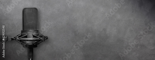 Microphone on dark gray concrete background, urban music or podcast banner with copy space photo