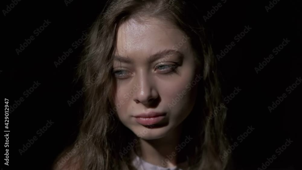 Close-up of girl with long light brown hair and grey eyes drinking coffee with pleasure from a white cup. Filmed in full face on a black background Close-up of girl with long light brown hair and grey eyes drinking coffee with pleasure from a white cup. Filmed in full face on a black background
