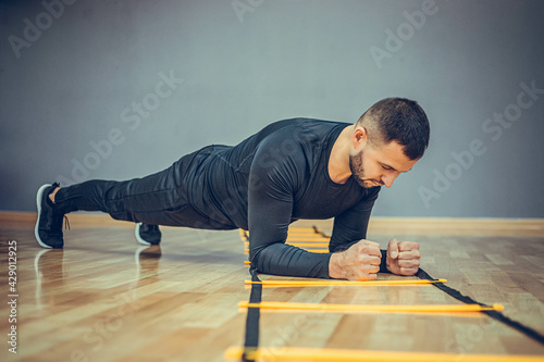 Fitness training athletic sporty man doing plank exercise in gym or home concept. Bearded man exercising workout aerobic at grey background.
