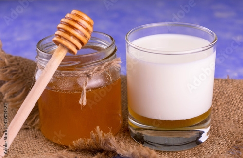 Glass of milk with honey on a blue background. Close-up.	