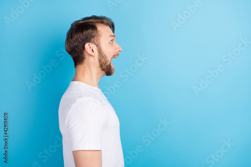 Profile portrait of impressed person open mouth look interested empty space isolated on blue color background