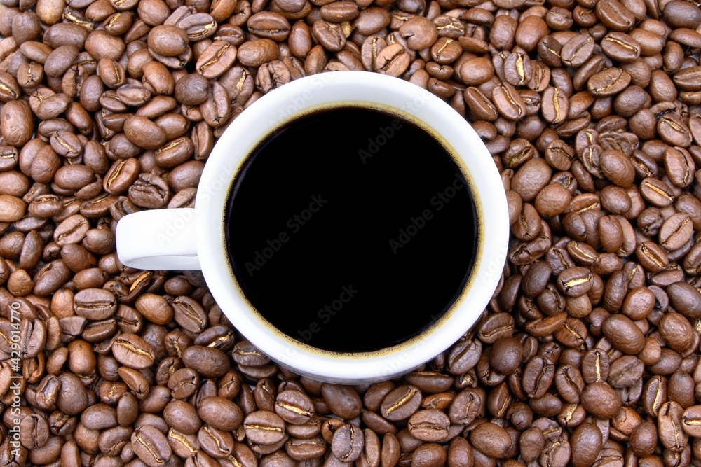 Coffee beans and cup of coffee background.Roasted coffee beans texture.Morning coffee Coffee beans and cup of coffee background.Roasted coffee beans texture.Morning coffee
