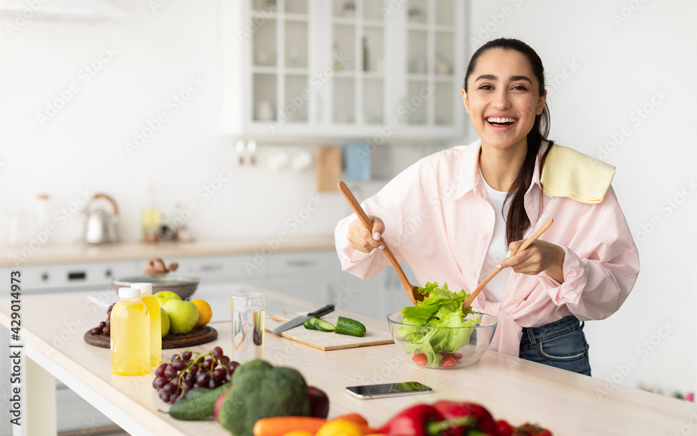Portrait of smiling young woman cooking fresh salad Portrait of smiling young woman cooking fresh salad