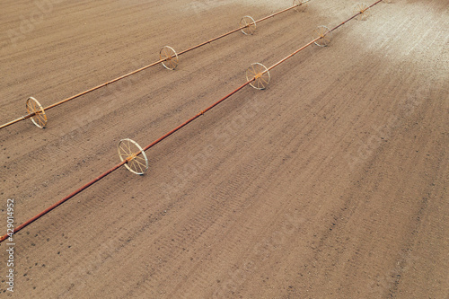 Wheel line irrigation equipment in ploughed field, aerial view