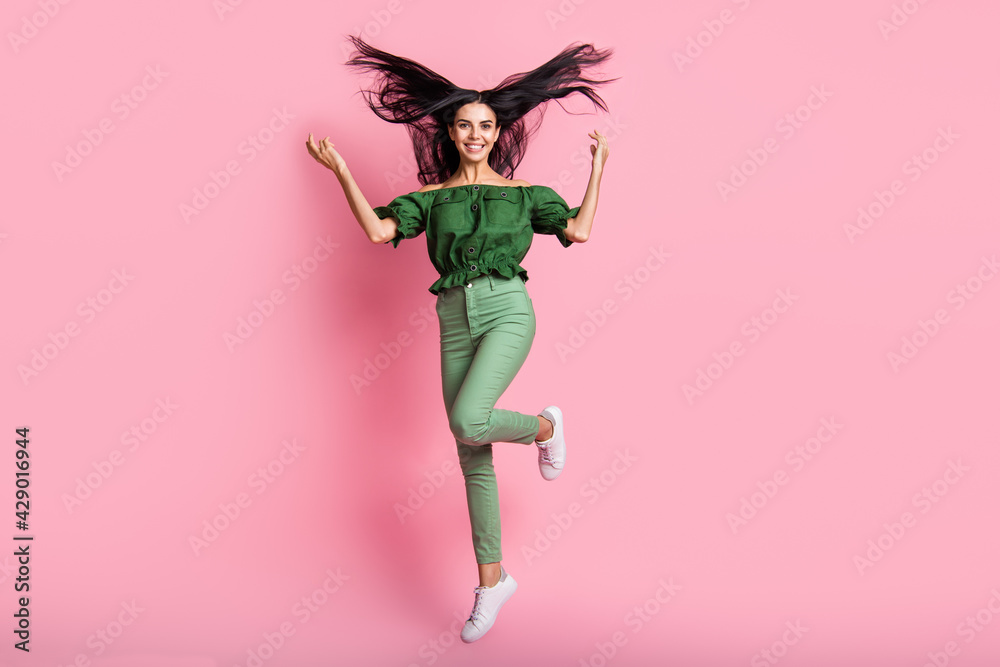 Full length body size view of attractive cheerful girl jumping having fun throwing hair isolated over pink pastel color background Full length body size view of attractive cheerful girl jumping having fun throwing hair isolated over pink pastel color background