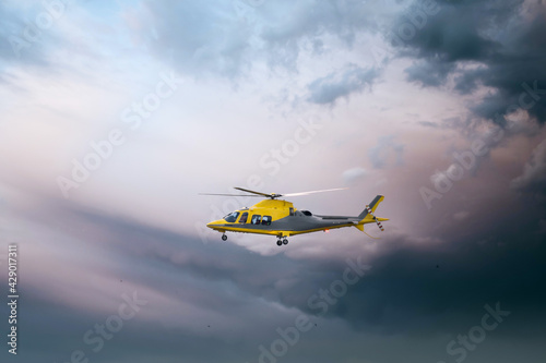 Air Ambulance helicopter yellow medical emergency chopper taking off at dusk amazing dramatic storm sky as respond to 999 incident medic team