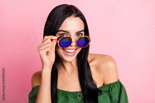 Photo of young cheerful girl happy positive smile hand touch sunglasses isolated over pink color background © deagreez
