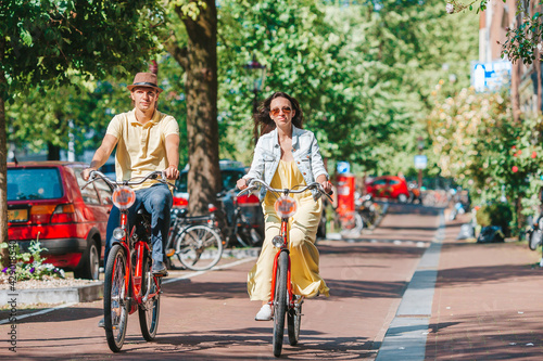 Photography Young happy caucasian couple on bikes in old streets in Amsterdam