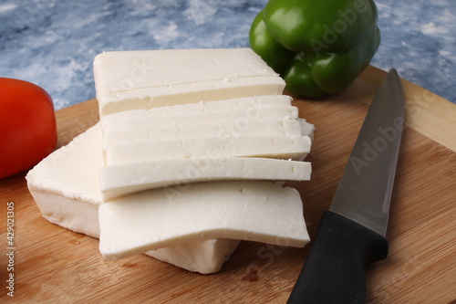 Paneer or cottage cheese with tomatoes, capsicum  and a knife on a wooden cutting Board. photo